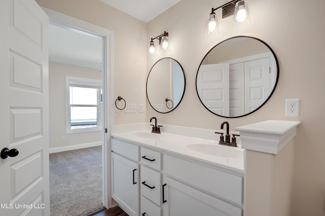 full bathroom with baseboards, double vanity, and a sink
