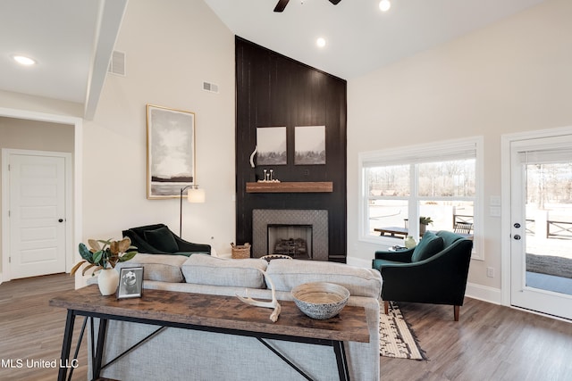 living room featuring hardwood / wood-style floors, a fireplace, high vaulted ceiling, and ceiling fan