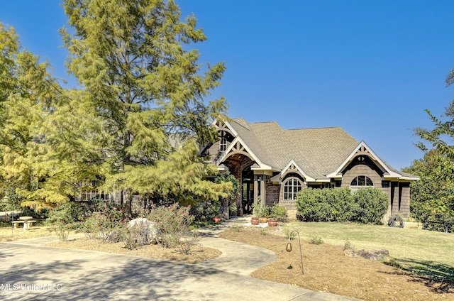 view of front of house with a front lawn and roof with shingles