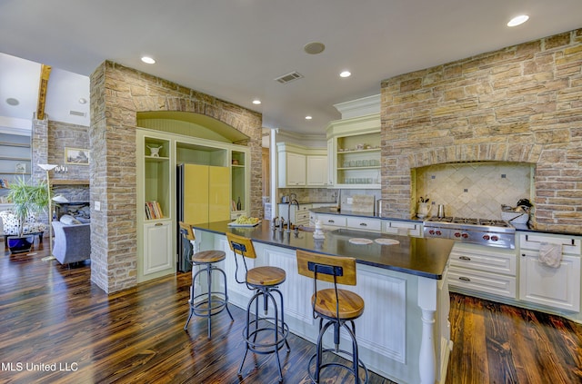 kitchen featuring dark wood finished floors, dark countertops, visible vents, freestanding refrigerator, and a fireplace