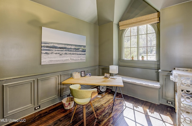 dining space with vaulted ceiling, a decorative wall, dark wood-style floors, and wainscoting