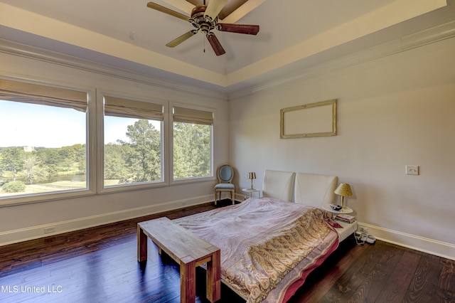 bedroom with a ceiling fan, baseboards, dark wood-type flooring, and a tray ceiling