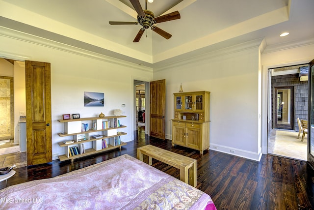 bedroom featuring a tray ceiling, dark wood finished floors, baseboards, ornamental molding, and recessed lighting