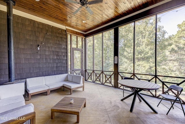 sunroom featuring an outdoor hangout area, a ceiling fan, and a wood stove