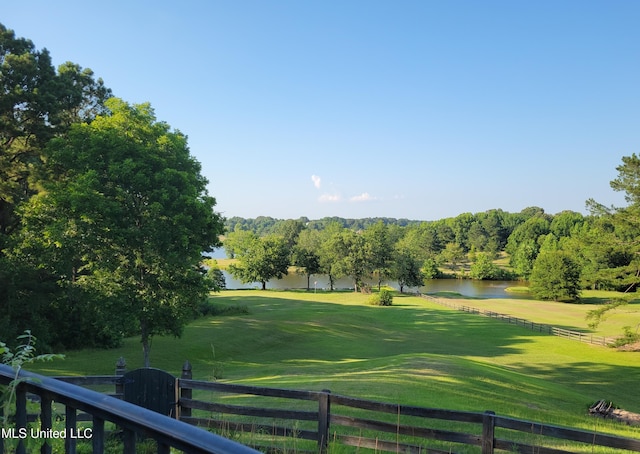 view of community featuring a yard, view of golf course, a water view, and fence