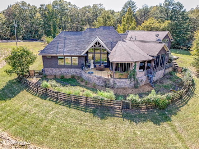 view of front of home with a patio area, a front lawn, stone siding, a shingled roof, and a fenced backyard