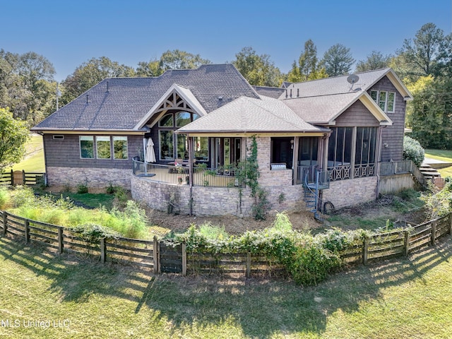 view of front of home with a sunroom, a fenced backyard, a front lawn, and roof with shingles