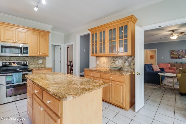 kitchen with a kitchen island, light tile patterned floors, light stone counters, stainless steel appliances, and crown molding