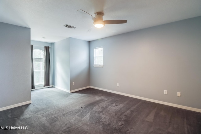 empty room with ceiling fan and dark carpet