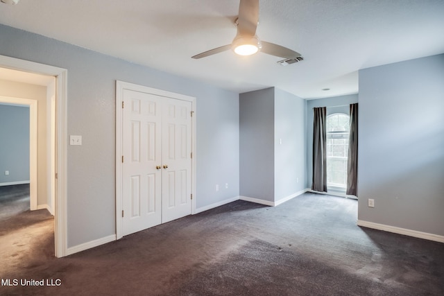 unfurnished bedroom with dark carpet, a closet, and ceiling fan