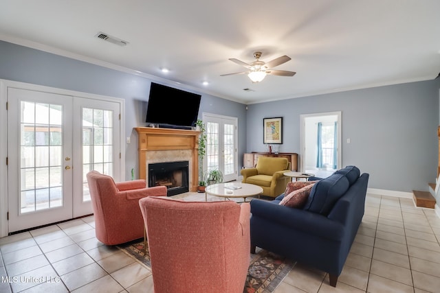 living room with a tile fireplace, crown molding, light tile patterned floors, and french doors