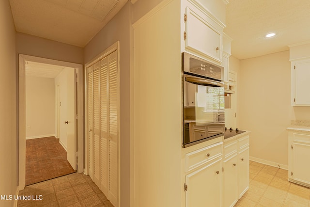 kitchen featuring recessed lighting, light floors, white cabinetry, and oven