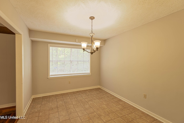 spare room with an inviting chandelier, baseboards, and a textured ceiling