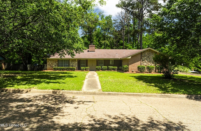 single story home with a front lawn, fence, stone siding, and a chimney