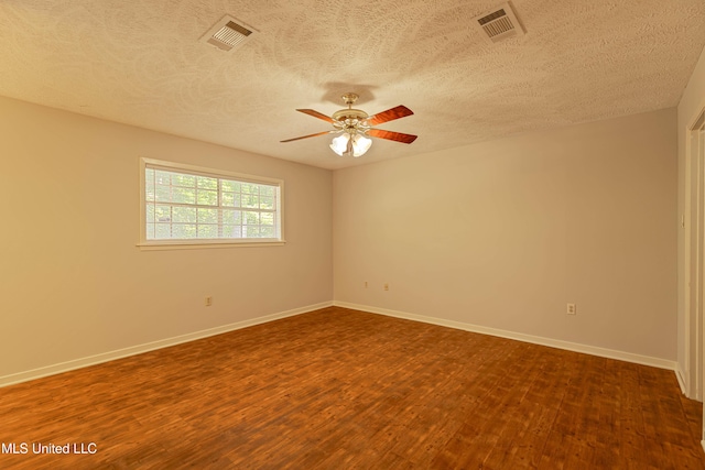 spare room with ceiling fan, dark wood-style flooring, a textured ceiling, visible vents, and baseboards