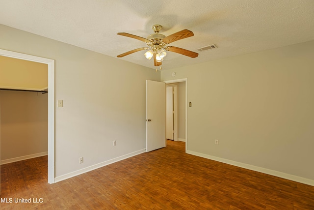 unfurnished bedroom with visible vents, a walk in closet, and wood finished floors
