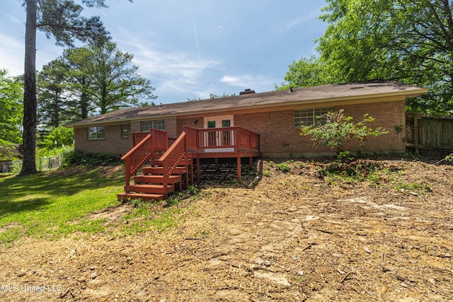 rear view of house featuring fence, a wooden deck, a yard, and brick siding