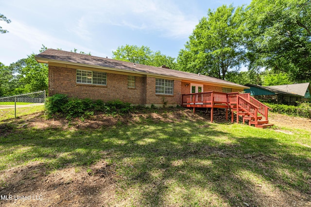 rear view of property featuring fence, brick siding, a wooden deck, stairway, and a lawn