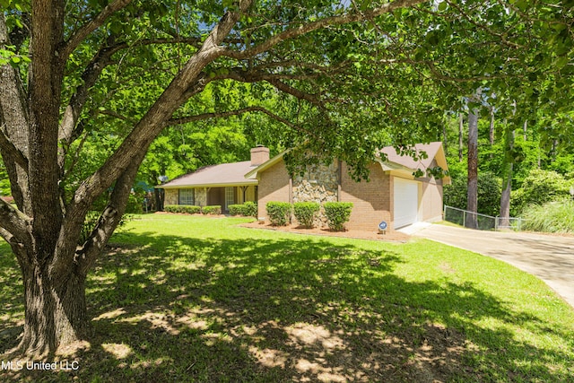 view of front of house featuring driveway, a chimney, a front yard, brick siding, and an attached garage
