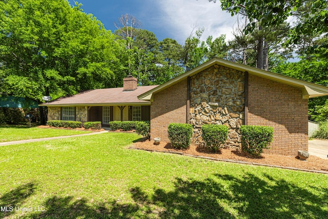 view of front of house with brick siding, a front lawn, stone siding, and a chimney