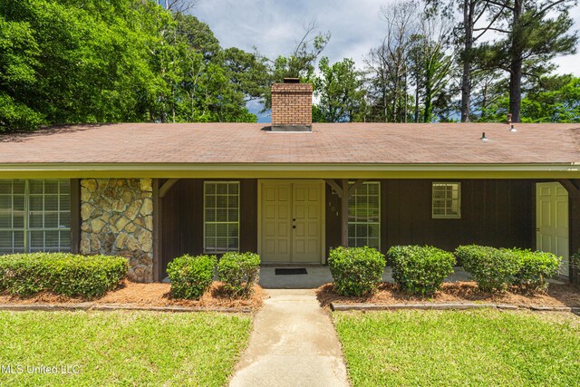 view of front of house featuring a front lawn, stone siding, and a chimney