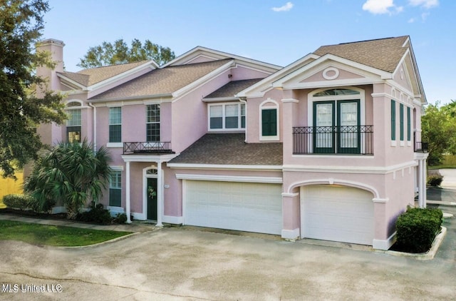 2252 Beach Dr Unit 305, Gulfport, MS 39507 - view of front of home featuring a garage, stucco siding, driveway, and a chimney