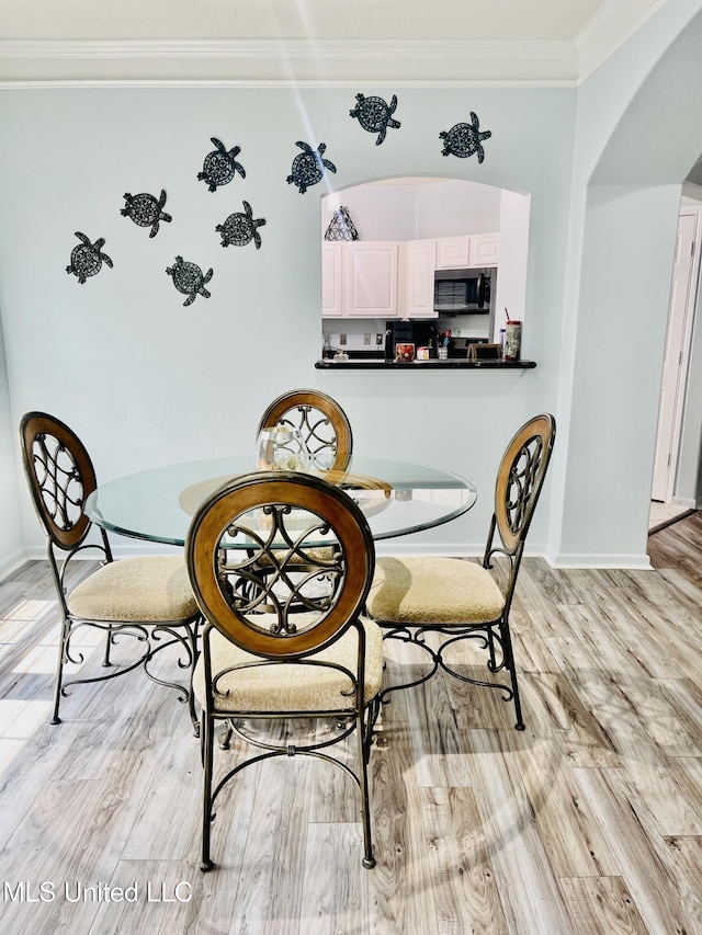 2252 Beach Dr Unit 305, Gulfport, MS 39507 - dining space with arched walkways, ornamental molding, light wood-style flooring, and baseboards