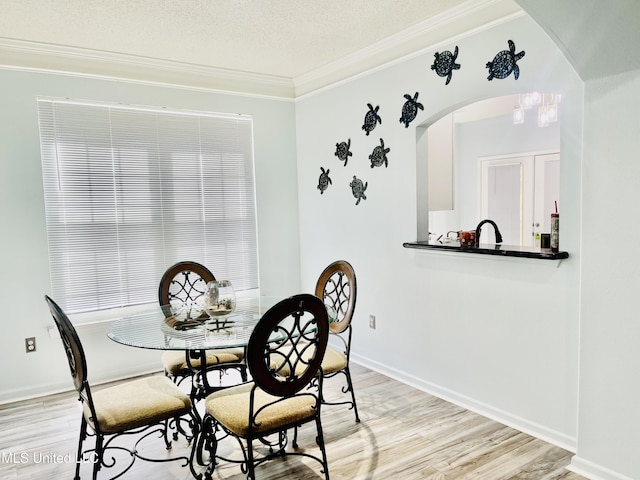 2252 Beach Dr Unit 305, Gulfport, MS 39507 - dining space featuring arched walkways, ornamental molding, light wood-style flooring, a textured ceiling, and baseboards