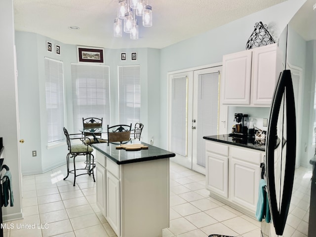 2252 Beach Dr Unit 305, Gulfport, MS 39507 - kitchen featuring freestanding refrigerator, dark countertops, white cabinetry, a kitchen island, and a textured ceiling