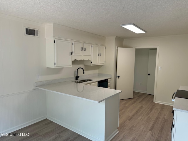 kitchen featuring dishwasher, sink, kitchen peninsula, light hardwood / wood-style floors, and white cabinets