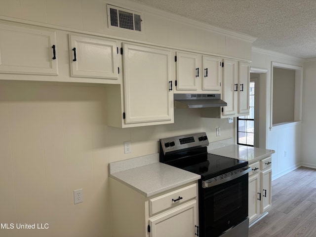 kitchen with stainless steel electric stove, white cabinets, a textured ceiling, ornamental molding, and light hardwood / wood-style floors