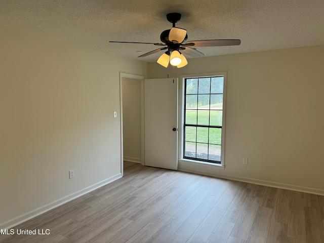 empty room with light hardwood / wood-style floors, a textured ceiling, and ceiling fan