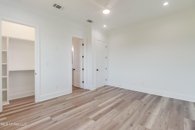 unfurnished bedroom with a walk in closet, light wood-type flooring, and a closet