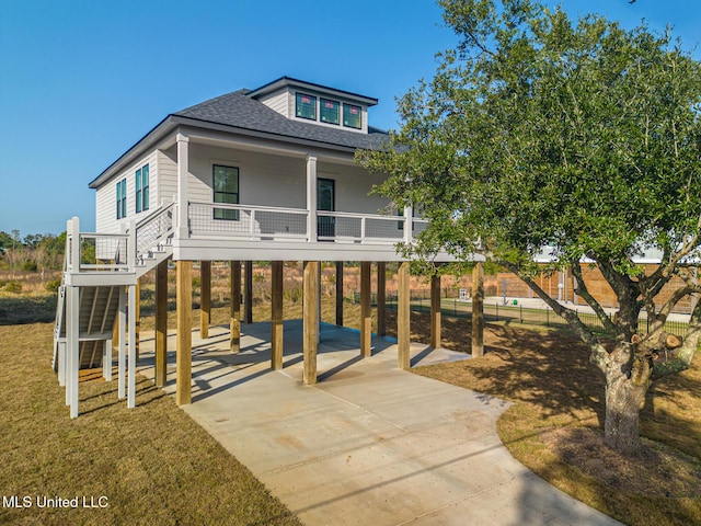 view of front of property with a carport, concrete driveway, a shingled roof, stairway, and a porch
