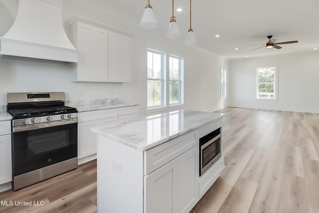 kitchen featuring white cabinets, custom range hood, and appliances with stainless steel finishes