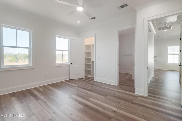 unfurnished bedroom with a walk in closet, light hardwood / wood-style flooring, and multiple windows