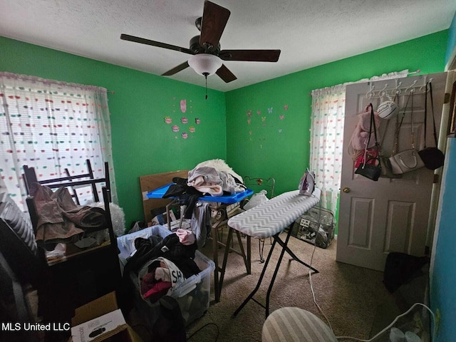 interior space with ceiling fan, a textured ceiling, and carpet flooring