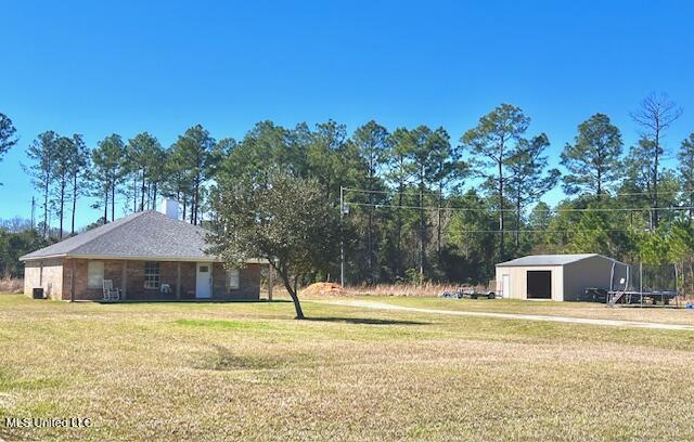 view of yard with a garage, a trampoline, and an outbuilding