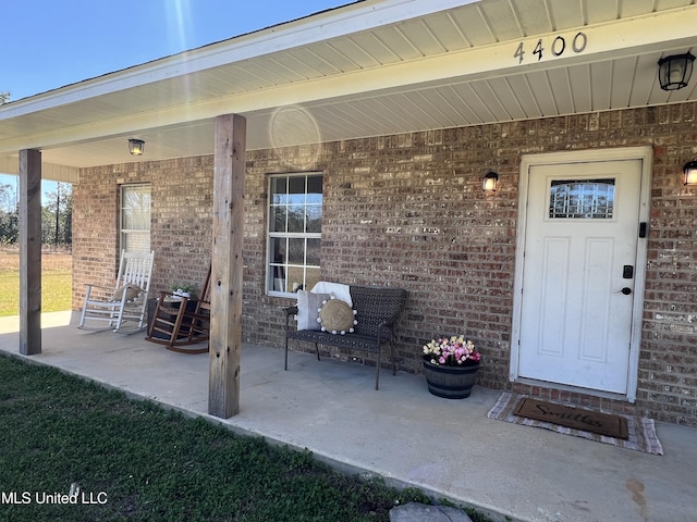 entrance to property featuring covered porch and brick siding