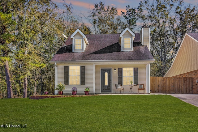 cape cod home featuring a lawn