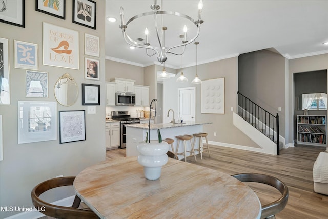 dining space with a notable chandelier, light wood-style flooring, ornamental molding, stairway, and baseboards