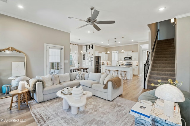 living room with stairs, light wood-style floors, and ornamental molding