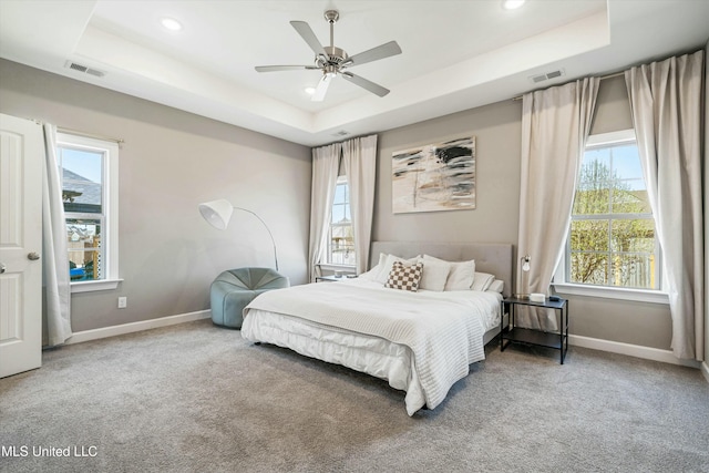 carpeted bedroom with recessed lighting, a tray ceiling, baseboards, and visible vents