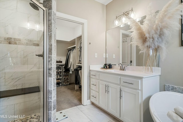 bathroom with a walk in closet, marble finish floor, a shower stall, a bathtub, and vanity