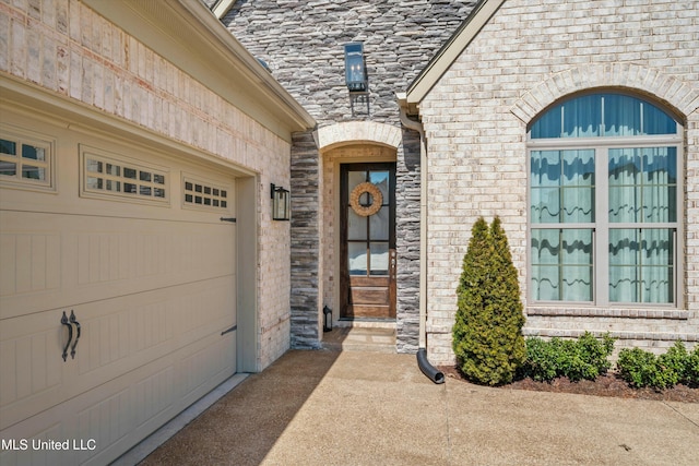 property entrance featuring an attached garage, brick siding, and stone siding