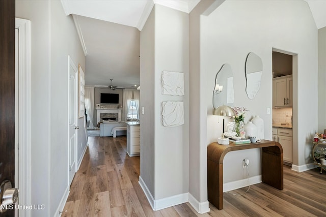 hall featuring light wood finished floors, baseboards, and ornamental molding