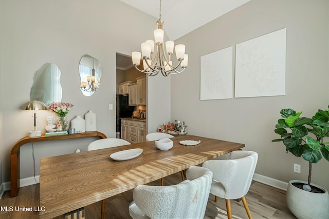 dining area with lofted ceiling, a notable chandelier, wood finished floors, and baseboards