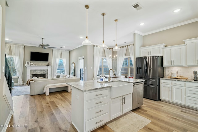 kitchen featuring a sink, backsplash, appliances with stainless steel finishes, a fireplace, and crown molding