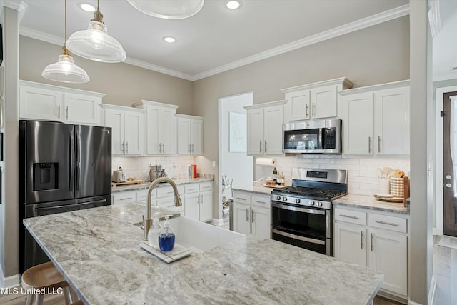 kitchen featuring a sink, ornamental molding, stainless steel appliances, white cabinetry, and a kitchen breakfast bar