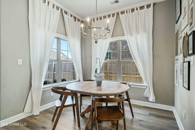 dining room with baseboards, wood finished floors, visible vents, and a chandelier